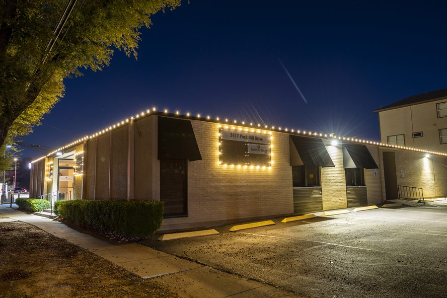 Commercial office building with warm white holiday lights outlining the roofline and signage at night