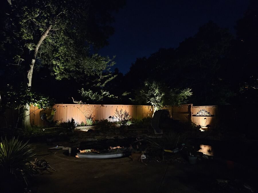 Fence and garden bed lighting around a backyard pond